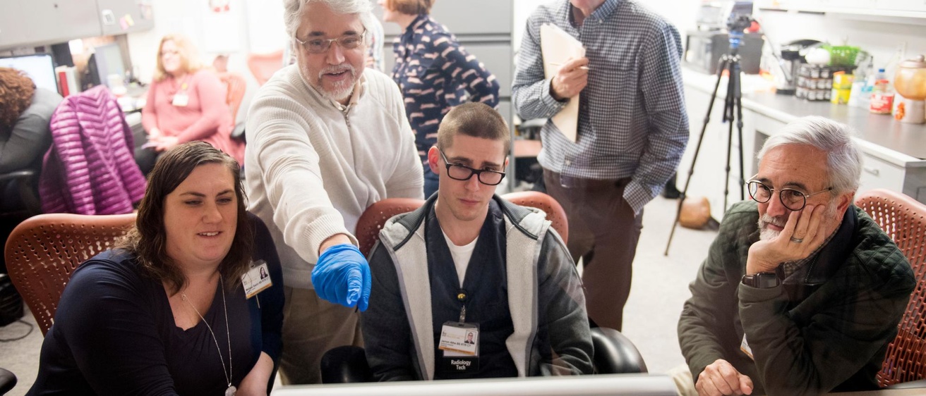 Some people standing around a computer