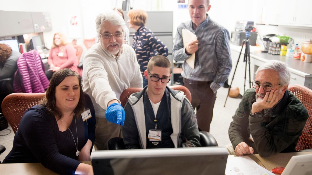Some people standing around a computer